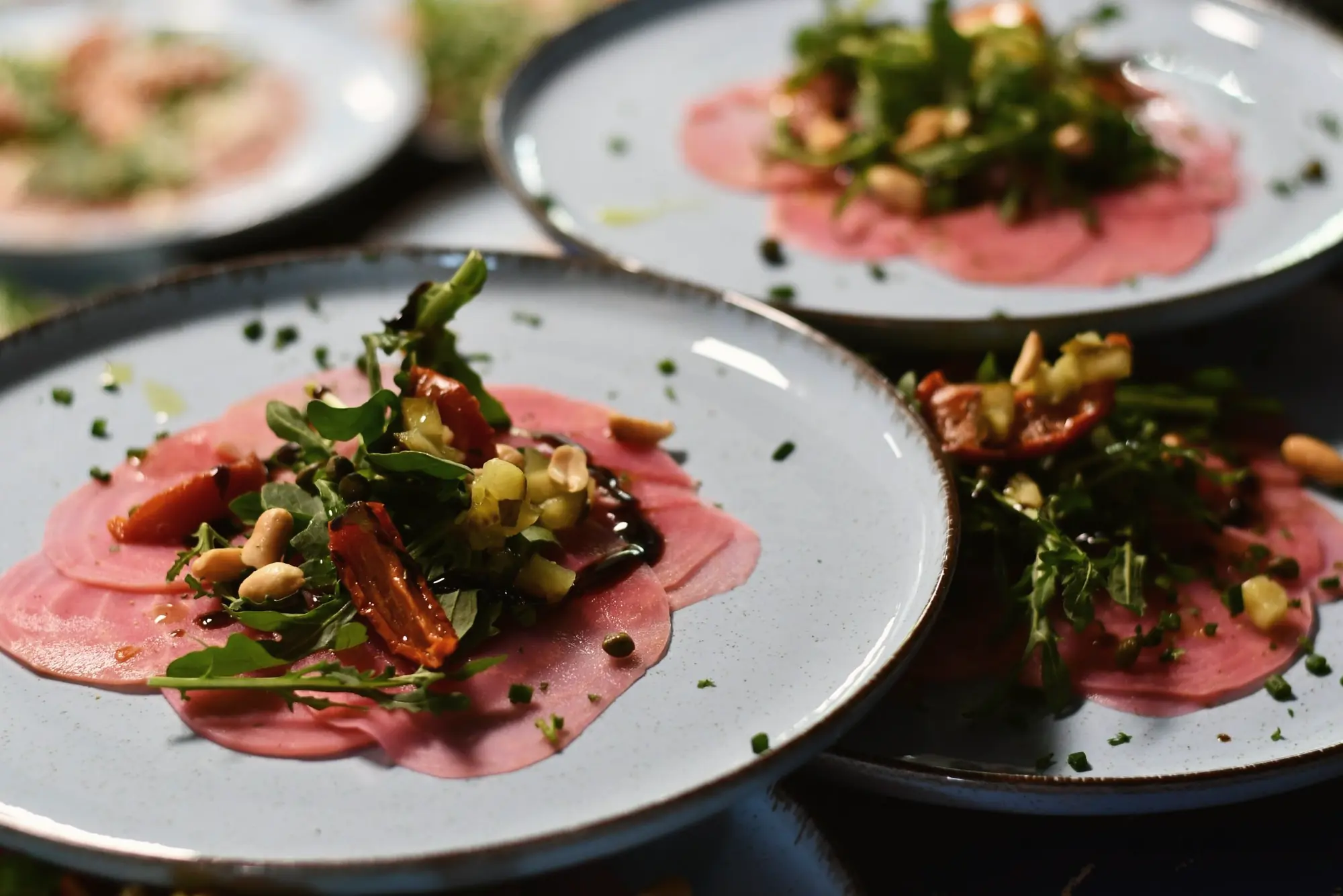 Borden met carpaccio, rucola en pijnboompitten, klaar om uit te serveren